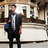 Portrait of male model in casual clothes poses confident on street during buildings. Traveler in new