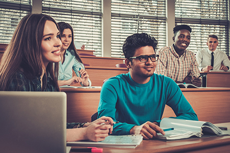 Multinational group of cheerful students taking an active part in a lesson while sitting in a lectur