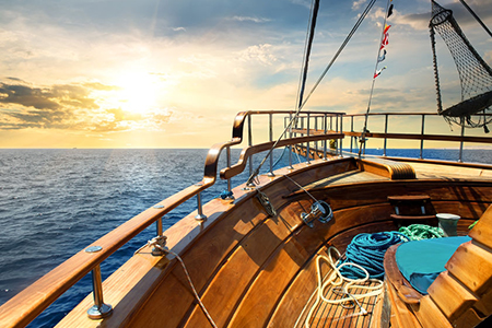 Wooden sailboat in the sea at sunrise