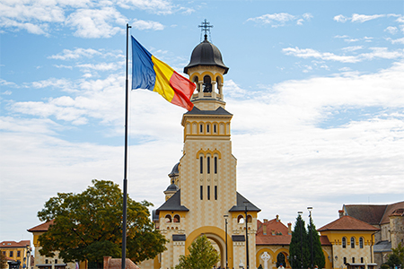 A scenic view of the Romanian flag against the Cathedral of the Coronation in Alba Iulia