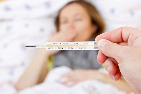 thermometer with fever reading over blurred image of sick person