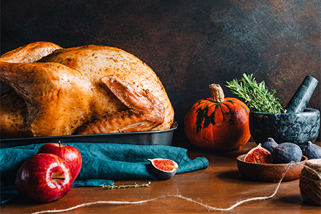 Festive table for Thanksgiving Holiday with whole roasted turkey with apple, pumpkin, figs and herbs