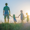 A large family is standing holding hands against the background of the sunset.