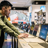 Focused ethnic man choosing laptop in shop