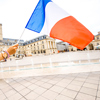 Holding french flag on the Liberation square backogorund in Dijon city in France