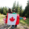 Family of mother with three kids hold large Canadian flag celebration in mountains