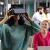 Smiling african american businesswoman wearing vr simulator by caucasian colleague at workplace