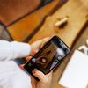 Woman hands taking a picture of a coffee cup with smart phone and laptop at a coffee shop.