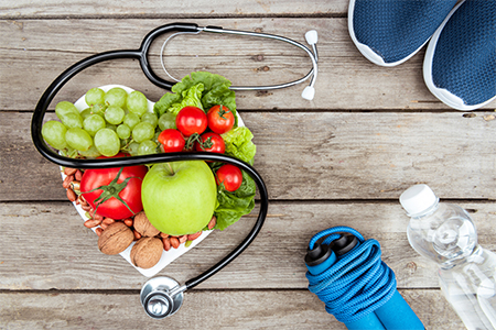 top view of stethoscope, organic vegetables and fruits and sport equipment on wooden surface