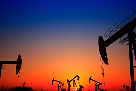 The oil pump, industrial equipment, on the background of the setting sun