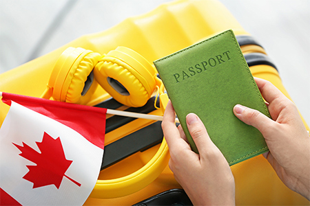 Woman with passport, Canadian flag and luggage, closeup