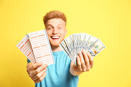 Happy young man holding lottery tickets and money