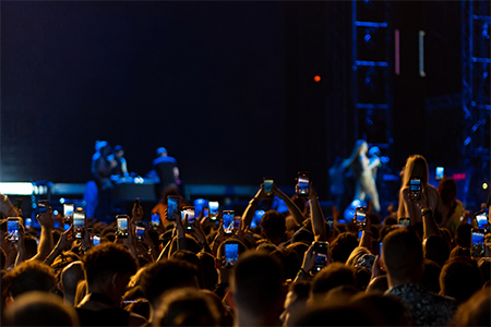 Closeup rear view of large crowd of people enjoying an open air concert on a summer night