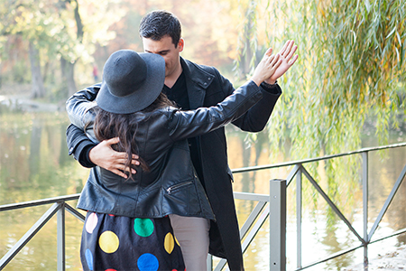 Beautiful dancing couple walking in autumn park near a lake