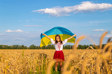 Child in a field of wheat with the flag of Ukraine