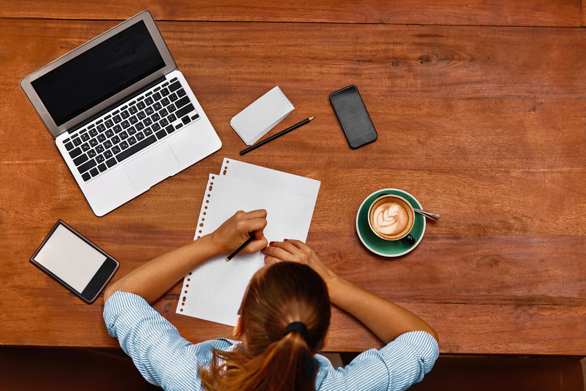 woman at desk with laptop and notebook