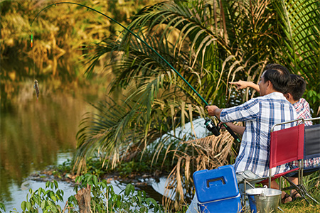 two people enjoying fishing by river