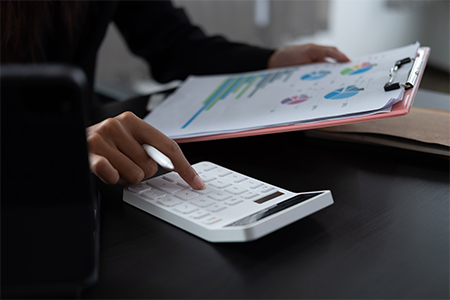 Woman with financial report and calculator to calculate report at the table in office.