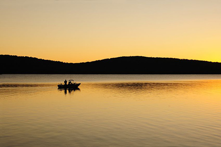 Silohuette of early morning fishing boat on a lake at dawn