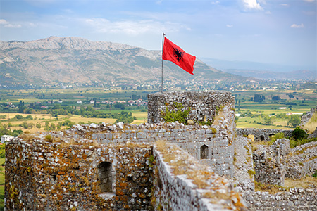 Red Albanian flag with double-headed black eagle waving over wall of Fortress Rozafa near Shkodra ci