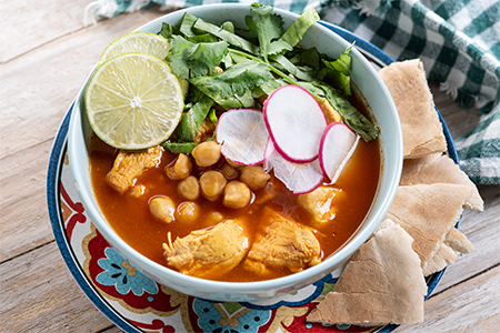 Traditional mexican red pozole soup on wooden table