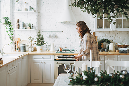 smiling woman with curly hair in plaid shirt bakes cookies at bright kitchen at home