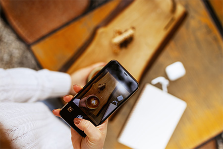 Woman hands taking a picture of a coffee cup with smart phone and laptop at a coffee shop.