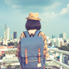 Back view of Asian woman traveler with backpack standing on the balcony with cityscape background