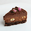 Slice of vegan chocolate nut cake on white blackground close-up