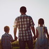 Father and children playing in the park at the sunset time