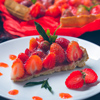 Strawberry tart with cream and mint on a black background.