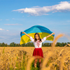 Child in a field of wheat with the flag of Ukraine