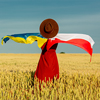 Girl with Ukraine and Poland flags in wheat field and blue sky