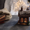 Winter house miniature illuminated and books on grey and white background