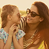 Happy fashion kid girl embracing her mother in trendy sunglasses smiling and looking on each other o