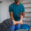 A close-up of physiotherapist exercising with senior patient's leg in a physic room