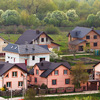 Street with new modern comfortable brick cottages with yards and blooming gardens on background