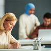 student with pencil giving test while sitting on desk