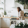 smiling woman with curly hair in plaid shirt bakes cookies at bright kitchen at home