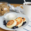 breakfast, circular syrniki, tvorozhniki or cheese cake with sour cream and hot drink on wooden tabl