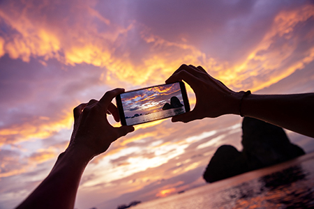 Closeup photo of hands taking a photo from mobile phone. Krabi province, Railay beach on background