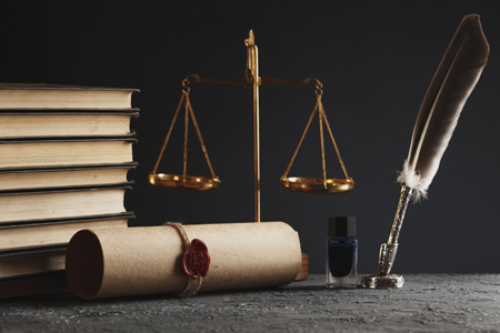 Law and justice concept. Gavel of justice, quill pen, old book and inkwell on dark background.