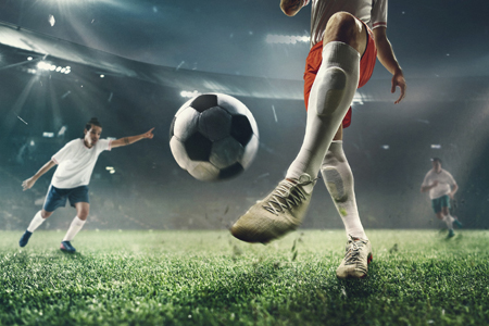 Exciting moment. Young male soccer or football players attacking at the stadium in flashlights, spot