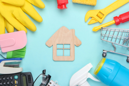 House with cleaning products on light blue background.