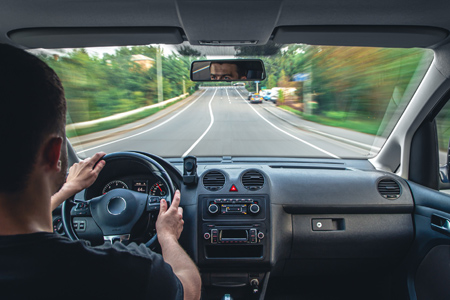 Man driving a car on the road. View from inside the car.