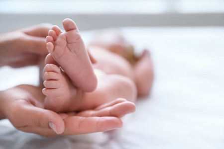 Mother and her newborn baby on bed, closeup. Space for text