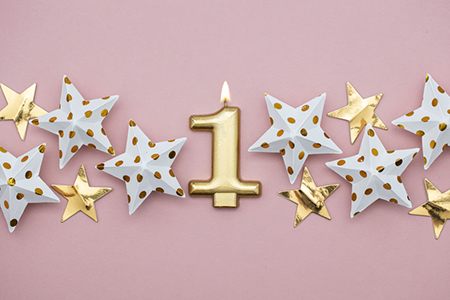 Number 1 gold candle and stars on a pastel pink background