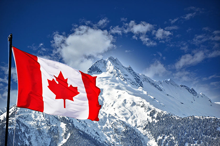 Mountains in Banff covered in snow - Canada flag in foreground