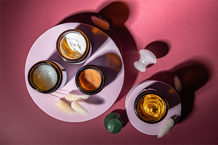 top view of cosmetics jars on pink background