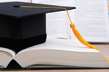 Black graduated tassel cap placed on the book.